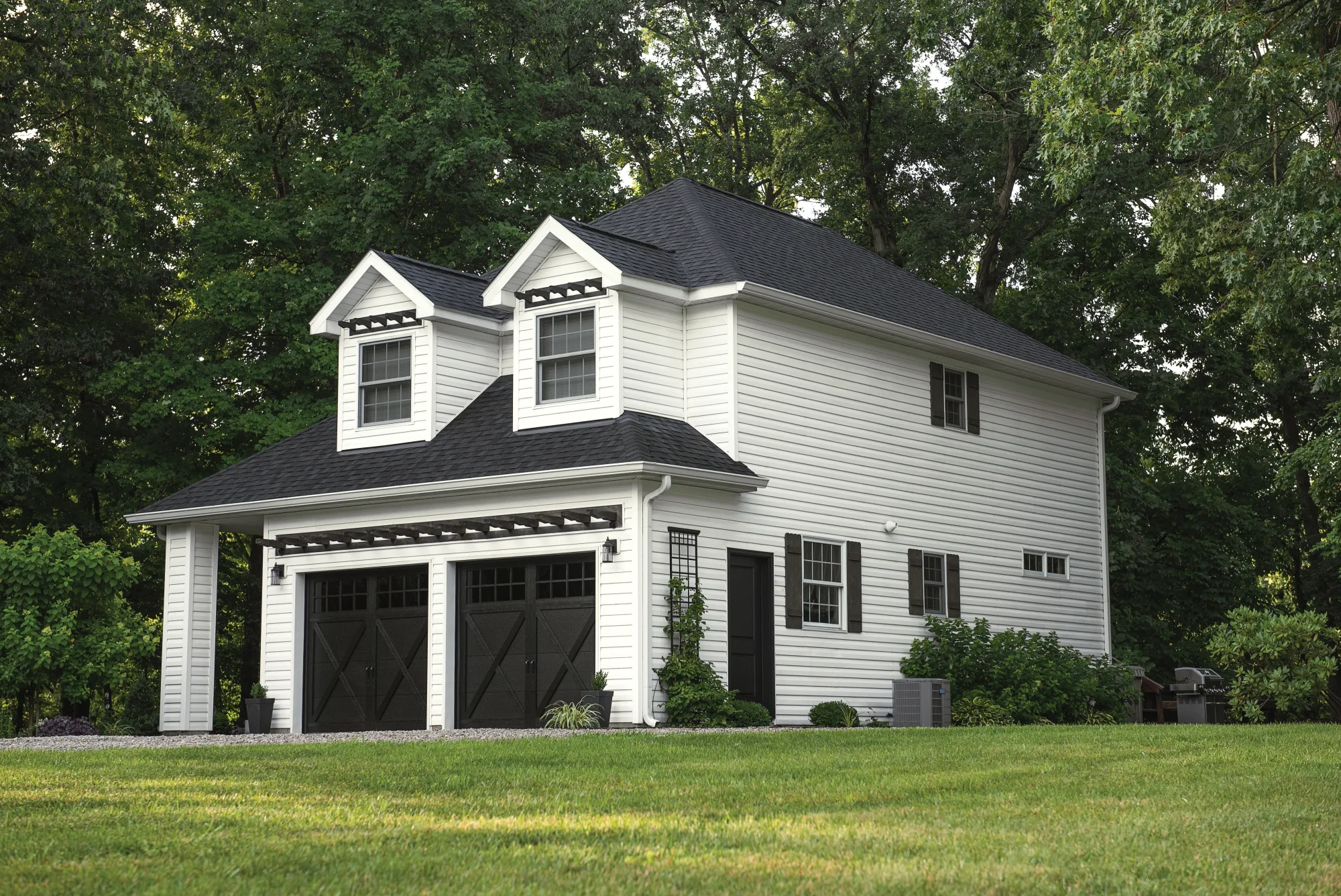 White farmhouse-style home with dark carriage-house garage doors